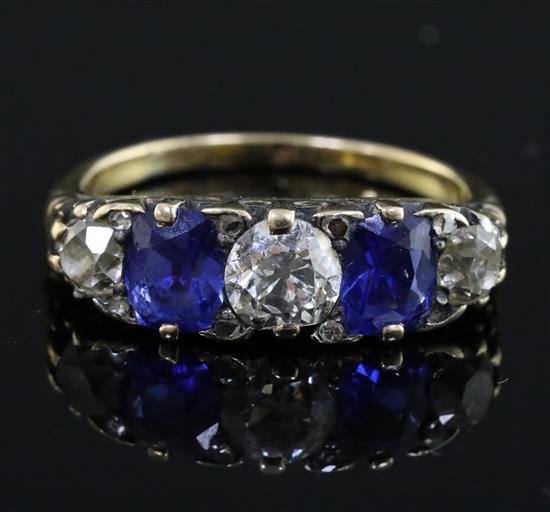 An early 20th century 18ct gold, graduated two stone sapphire and three stone diamond half hoop ring, size P.